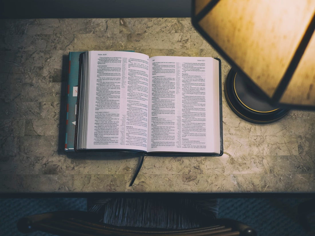 Open book beside a table lamp in the evening