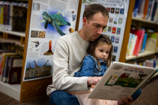 Father reading a book to his daughter in a library